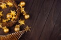 Cozy dark Christmas background with golden balls, spruce, wreath, stars on glowing garland on brown wooden table as festive border Royalty Free Stock Photo