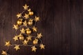 Cozy dark christmas background with golden christmas tree shape of decoration - balls, stars on glowing garland on brown wooden. Royalty Free Stock Photo
