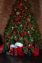 Cozy decorated living room for Xmas. Toy vintage train on floor under decorated Christmas tree and gifts. Red sack santa claus wit