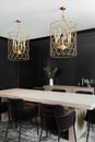 A black dining room with wainscoting walls and gold chandelier.