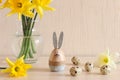 Cozy Easter background with decorative eggs, Easter bunny, daffodils on the table. Holiday greeting card. Selective