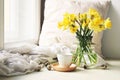 Cozy Easter, spring still life scene. Cup of coffee, wooden plate, quail eggs and vase of flowers on windowsill. Floral