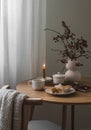 Cozy evening - a cup of tea, muffins, cranberry branches, a bouquet in a vase, a notebook, a burning candle on a round wooden