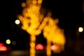 Cozy evening in the festive city. Blurred image of trees decorated with light garlands for Christmas and New Year celebration time