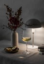 Cozy evening home still life -  glass of wine,  lit lamp on the table. Scandinavian style interior Royalty Free Stock Photo