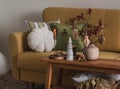 Cozy evening living room - yellow sofa with pillows, wooden bench with Christmas decor and candles in a brass candlestick. Cozy Royalty Free Stock Photo