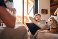 Cozy family tea time. Father and son at the home living room. Boy lying on comfortable sofa and  stroking their beagle dog and Royalty Free Stock Photo