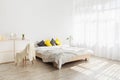 Cozy, feminine bedroom with throw pillows and plants at white blank wall