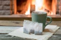 Cozy fireplace and a cup of tea and teabags, in country house, winter vacation Royalty Free Stock Photo