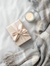 Cozy flat lay with gift box, candle, and blanket on subtle grey background Royalty Free Stock Photo