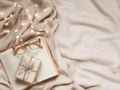 Cozy flat lay scene with open book, glasses, gift box, and string lights on soft fabric Royalty Free Stock Photo