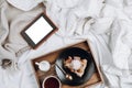 Cozy flatlay of bed with wooden tray with vegan apple pie, ice cream, black tea and tablet or ebook
