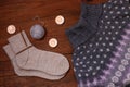 Cozy flatlay. Winter concept. Flat lay of knitted sweater, candles, needles and yarn on wooden background. Warm weekend