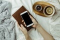 Cozy flatlay of woman`s hands holding smartphone with black scre