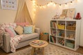 Cozy kids room interior with table, sofa and shelving unit Royalty Free Stock Photo
