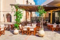 Cozy Greek restaurant in shade with wooden chairs