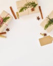 Cozy holiday background in warm, trendy colors and white. Christmas composition of spruce branches, gift, cinnamon, anise and