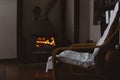 Cozy home dark interior with an armchair near fireplace with blazing fire. Calm Royalty Free Stock Photo