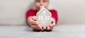 Cozy small home model with windows in woman hand on grey background. Christmas and happy new year composition. Bright Royalty Free Stock Photo