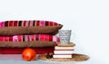 Cozy home interior decor: cup of coffee, apple, stack of books, pillows and plaid on a white table. Distance home education.