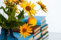 Cozy home interior decor: stack of books and vase with yellow flowers on a table. Distance home education.Quarantine concept of Royalty Free Stock Photo