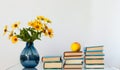 Cozy home interior decor: stack of books and vase with yellow flowers on a table. Distance home education.Quarantine concept of Royalty Free Stock Photo