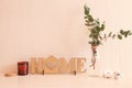 Cozy home interior. Wooden decor with the inscription HOME, a vase with eucalyptus sprigs, cotton flowers and a