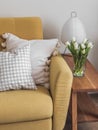 Cozy home interior. A yellow sofa, a wooden bench with a paper lamp, a bouquet of tulips in a vase in the living room interior Royalty Free Stock Photo