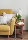A cozy home interior. A yellow sofa, a wooden bench with a paper lamp, a bouquet of tulips in a vase, a magazine in the living Royalty Free Stock Photo