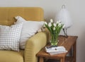 A cozy home interior. A yellow sofa, a wooden bench with a paper lamp, a bouquet of tulips in a vase, a magazine in the living Royalty Free Stock Photo