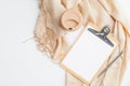 Cozy home office desk with beige blanket, cup of coffee, clipboard with empty paper note on white background. Flat lay, top view.