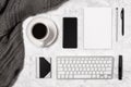 Cozy home office workspace. Marble desk with wool plaid, coffee cup, mobile phone, keyboard, blank paper and notepad