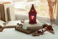 Cozy home still life: candlestick and books on windowsill against landscape outside. Autumn holidays, reading time concept. Royalty Free Stock Photo