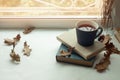 Cozy home still life: candlestick and books on windowsill against landscape outside. Autumn holidays, reading time concept