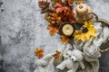 Cozy home still life - knitted blanket in a straw basket, pumpkin, bouquet of maple leaves, candle on a gray background, top view