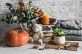 Cozy home still life. Stack of books, pumpkin, dry autumn branches, candle, winter sweaters, teddy bear on the table. Cozy home Royalty Free Stock Photo