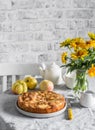 Cozy home tea party table - apple pie, bouquet of yellow flowers, teapot on a light table on a light background Royalty Free Stock Photo