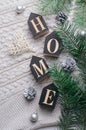 Cozy Winter Concept, Pine Branches and Home Letters on Beige Knitted Background, Top View