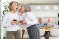 Elderly women have withdrawn from their male companions, stand with glass of wine in hands, chatting Royalty Free Stock Photo