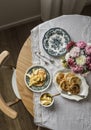 Cozy homemade breakfast - pancakes with apple sauce, vintage dishes, a bouquet of dahlias on a retro tablecloth on a wooden table