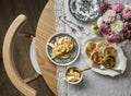 Cozy homemade breakfast - pancakes with apple sauce, vintage dishes, a bouquet of dahlias on a retro tablecloth on a wooden table