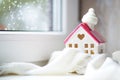 Cozy house is wrapped in a hat and scarf in a snowstorm -window sill decor. Winter, snow - home insulation, protection from cold Royalty Free Stock Photo