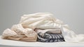 cozy image of a pile of folded fabric on a white background. The fabric has various shades of white, beige and gray