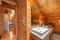 Cozy interior of bathroom in a country cottage with wooden walls and a view to a bedroom. Decorated corner with sink Royalty Free Stock Photo