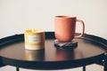 Cozy interior details. Little round table with ceramic cup of delicious tea and yellow aromatic candle. Resting after busy work Royalty Free Stock Photo