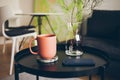 Cozy interior details. Little round table with ceramic red color cup of delicious earl gray tea. Resting after work day, offline Royalty Free Stock Photo