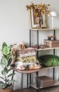 Cozy interior of the living room - a chair with a stack of warm blankets, a rack with autumn decor in Scandinavian style