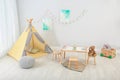 Cozy kids room interior with table, play tent