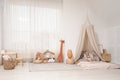 Cozy kids room with play tent, toys and floor bed. Montessori interior Royalty Free Stock Photo