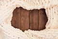 Cozy cream colored knitted thick wool blanket, overhead view frame on a rustic dark wood background